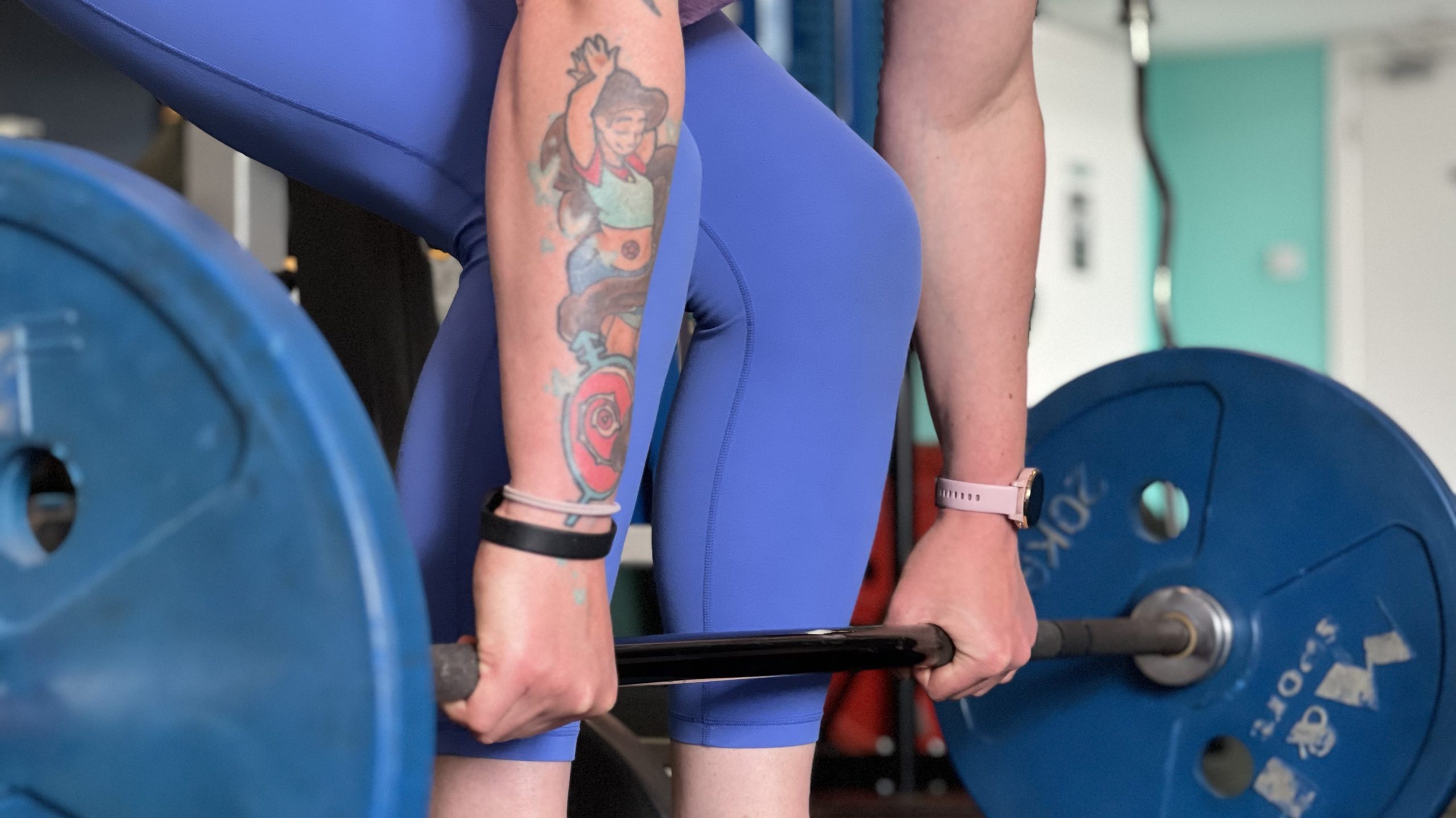 Arms and legs of a white person at the bottom of a barbell deadlift
